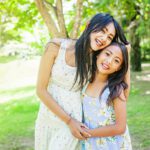 A couple of asian sisters hugging each other on a background of a summer park